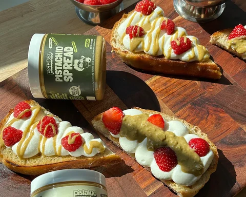Toasted sourdough topped with whipped mascarpone, raspberries, and pistachio drizzle